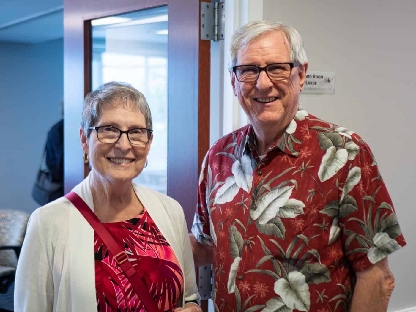 A retirement age man and woman pose for a photo indoors