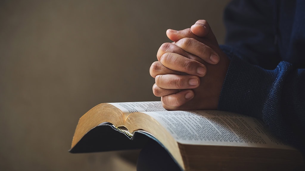 person praying over bible